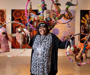 Artist Rhonda Sharpe, with her work, as part of the installation of soft sculptures by Yarrenyty Arltere Artists - Desert Mob 2021 image credit: Emma Louise Murray/Courtesy Araluen Arts Centre