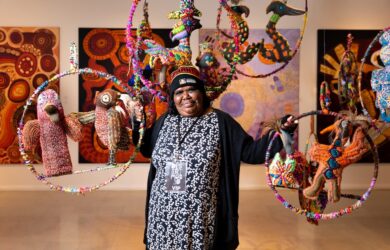 Artist Rhonda Sharpe, with her work, as part of the installation of soft sculptures by Yarrenyty Arltere Artists - Desert Mob 2021 image credit: Emma Louise Murray/Courtesy Araluen Arts Centre