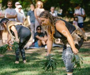 Two Djirri Djirri dancers performing with leafy branches as community members watch during Yaluk Langa Community Day at Heide Museum of Modern Art.