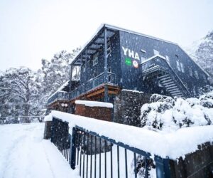 YHA Thredbo lodge in heavy snowfall, with snow covering the building and surrounding landscape.