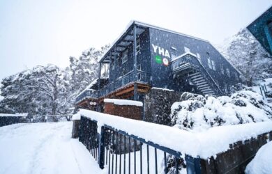 YHA Thredbo lodge in heavy snowfall, with snow covering the building and surrounding landscape.