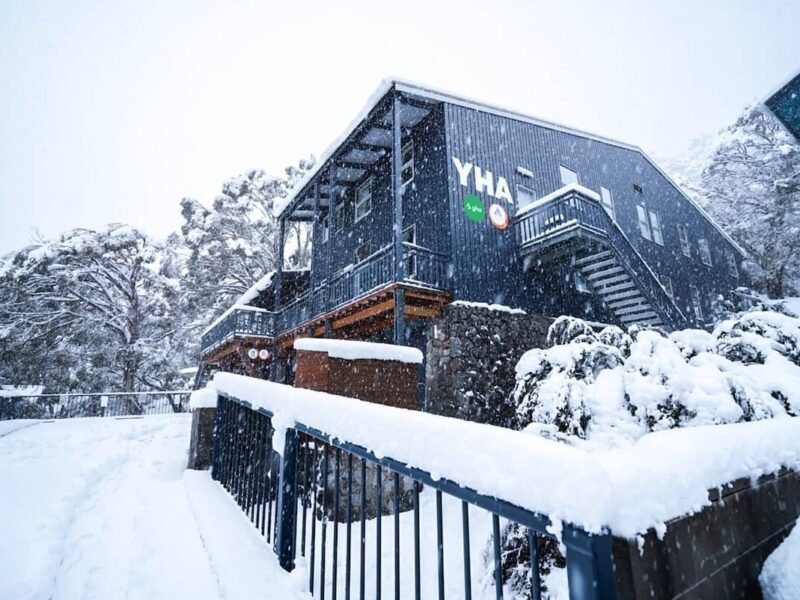YHA Thredbo lodge in heavy snowfall, with snow covering the building and surrounding landscape.