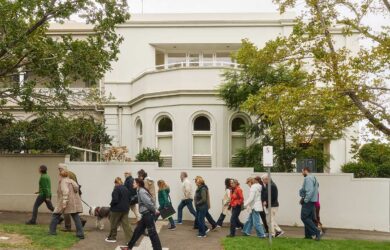 Photo of a group of adults walking together past a historic building in South Yarra